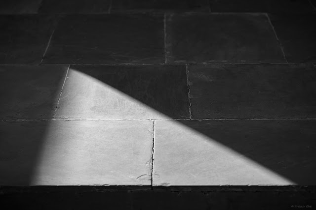 A Minimalist Photograph of a Right angled Light Triangle as seen on the floor at Jawahar Kala Kendra Jaipur, shot in black and white.