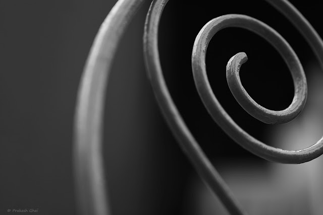 A Black and White Minimalist Photo of a Metal Spiral or a Fibonacci Spiral