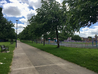 A paved path with a playground to the right of it.