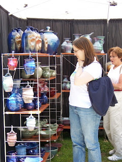 Young woman shopping for pottery in a craft booth.