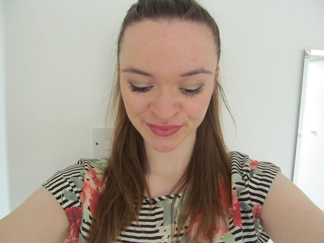 girl looks down with brown ponytail, light makeup and black and white striped top with floral pattern