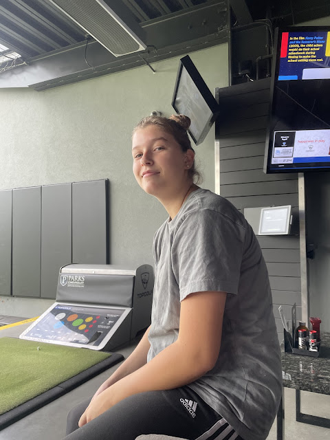 Elizabeth smiling at the camera while sitting on a chair at top golf