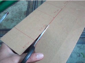 Memotong kardus yang telah dipola untuk Cara Membuat Tempat Pensil Cantik Dengan Kain Flanel