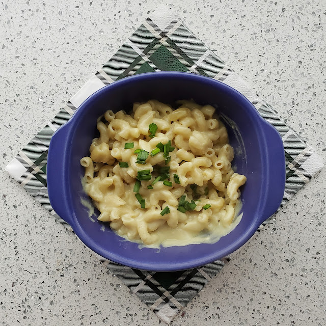 Vegan mac and cheese in a purple bowl on a plaid napkin