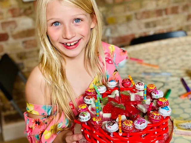 A sweetie cake with the candles blown out. It has lollipops and liquorice around the edge and is filled with sweets