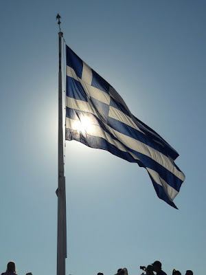 Bandera griega ondeando al viento en el espolón Este de la Acrópolis de Atenas
