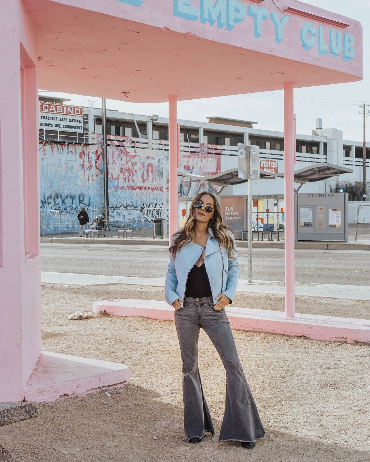 Girl standing in suede blue jacket at abandoned pink gas station