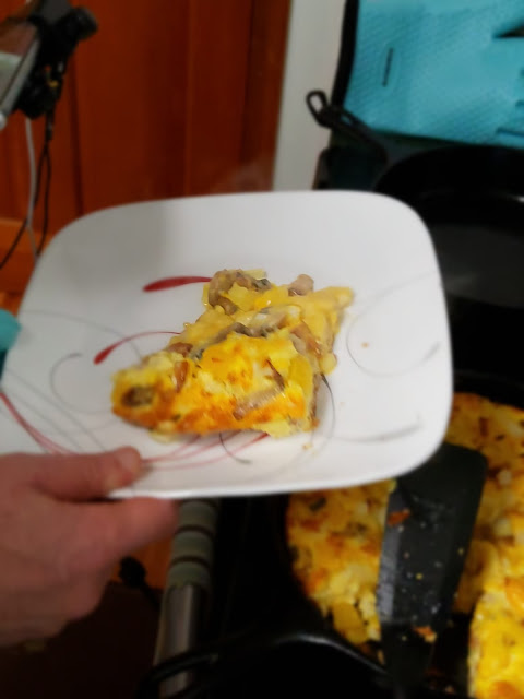 A slice of a frittata sits on a plate being carried