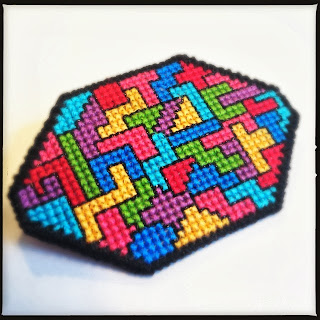 Korssting broderet broche i geometrisk mønster. Lavet af plastik kanvas. Cross stitch embroidered broche in geometric pattern.