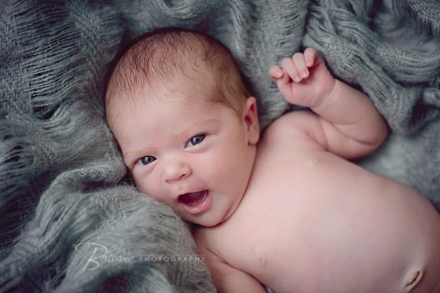 cheeky and cute newborn baby looking up while on grey blanket