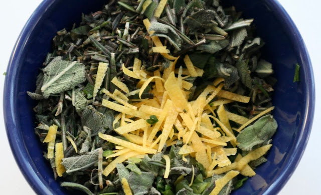 rosemary, sage, lemon zest in a dark blue bowl