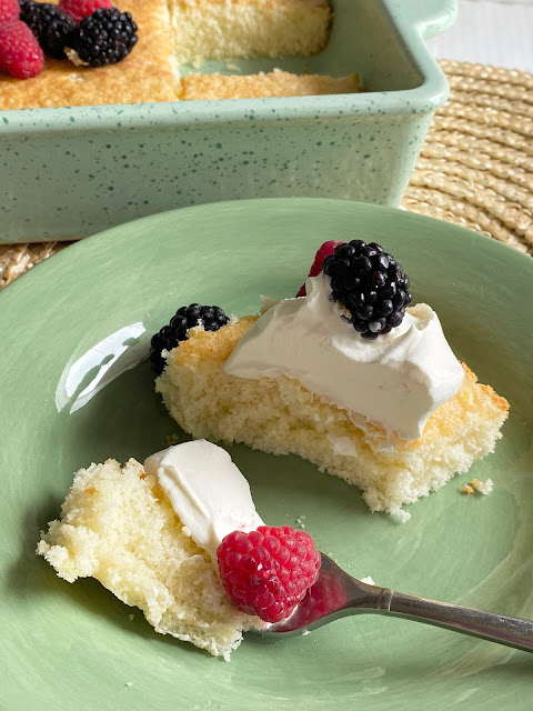 Hot Milk Sponge Cake with Cool Whip and fresh berries on a green serving plate.