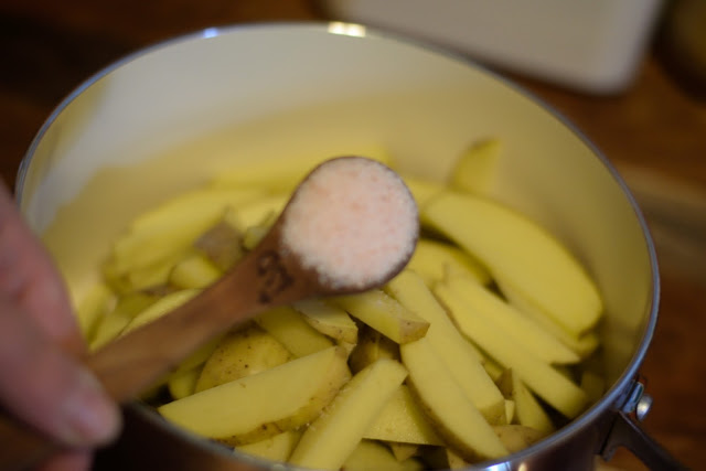 Salt being added to the pot with the fries in it.