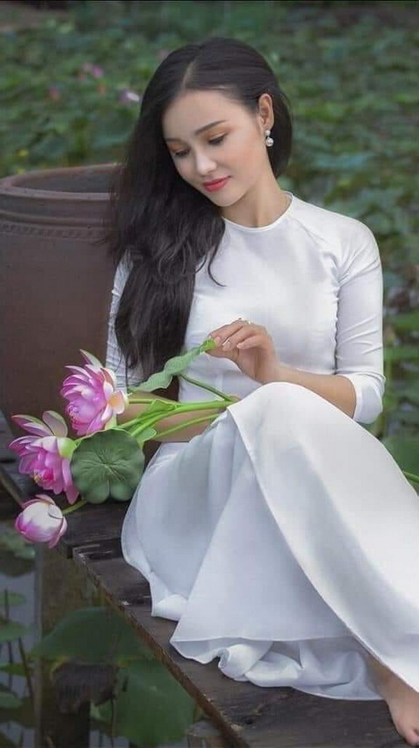 Thiếu nữ ngồi áo dài trắng cầm hoa