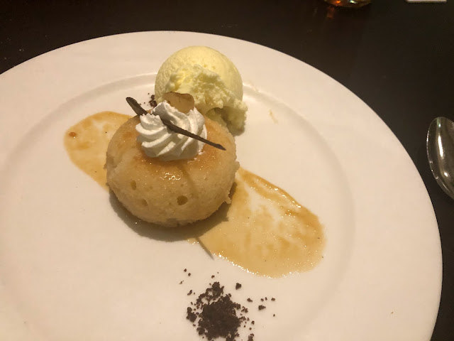 A spherical rum cake on a plate with a scoop of vanilla ice cream