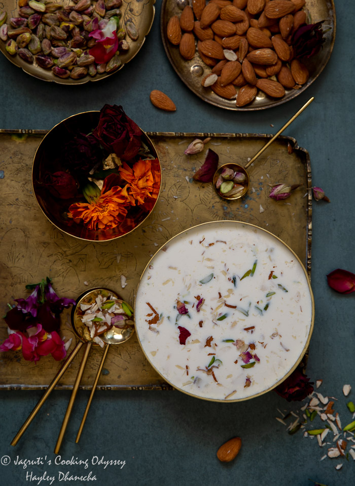 Traditional creamy basundi served in a brass bowl topped with slivered nuts and dried rose petals