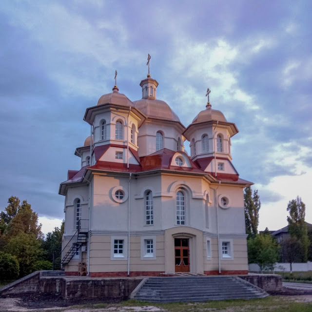 Русская православная церковь молдавского городка Купчинь в освещении уходящего солнца, пробившегося между горизонтом и тучами