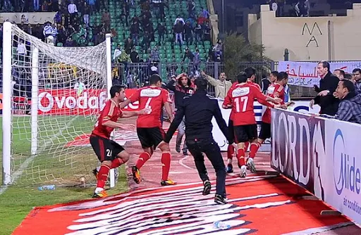 Al-Ahly players escape from the field as fans of Al-Masry rush after them