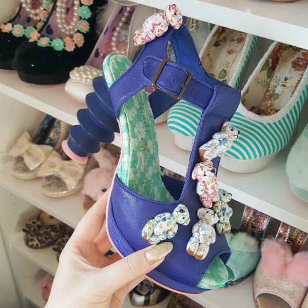 Irregular Choice Hot Shot sandal in hand in front of shoe shelves