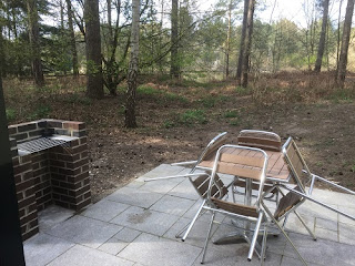 A small patio area with a small brick parbeque area on the left and a table with four chairs on the right.