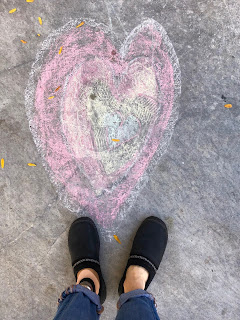 My feet (one real, one prosthetic) on the sidewalk below a chalk-drawn heart.