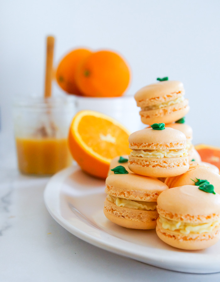 Orange Macarons stacked on white platter