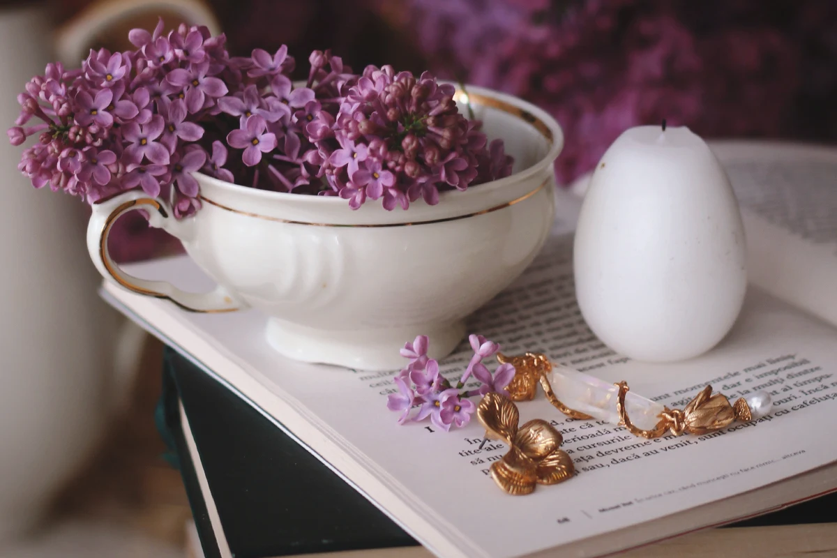 close-up of golden earrings laying on top of an opened book close to a cup of coffee and aesthetic flowers