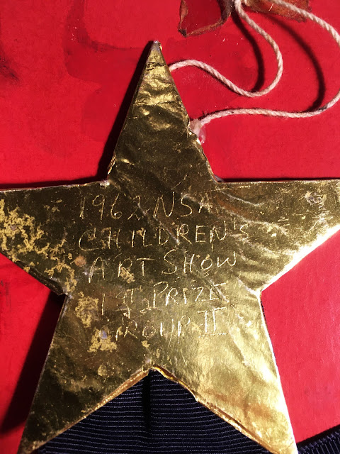 Close up of gold star, with scratched inscription: "1962 NSA Children's Art Show First Prize Group II