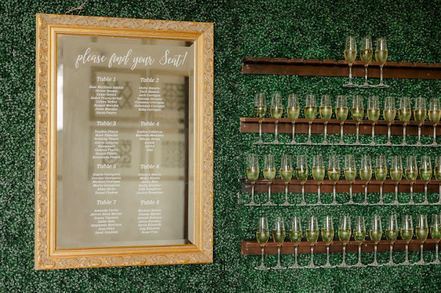 hedge wall with seating chart on mirror and champagne flutes