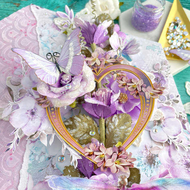 Purple Haze mixed media canvas created with: Prima aquarelle dreams paper, flowers, ephemera, acetate, lace, Reneabouquets butterflies, printed chipboard heart; Tim Holtz distress oxide milled lavender; Pinkfresh clear drops iridescent