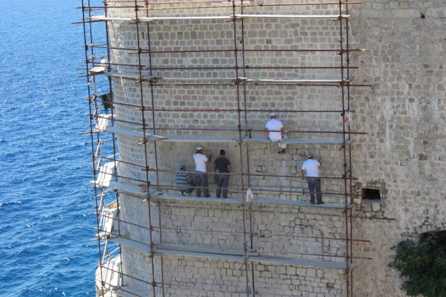 Dubrovnik, werkers aan de stadsmuur, hangend boven zee