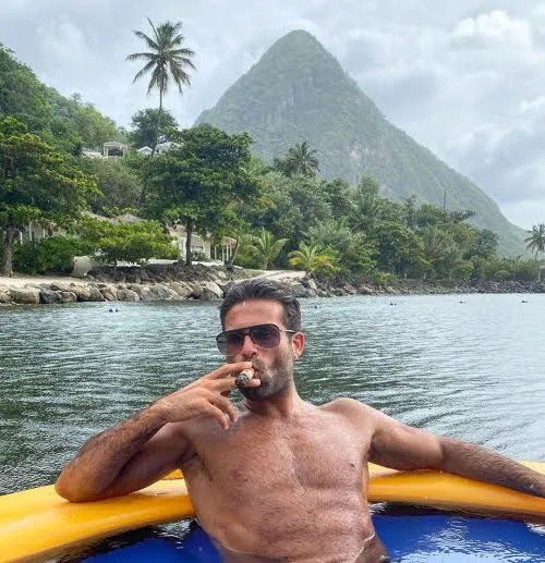 Gorgeous tan man from the waist up lounging smoking a cigar