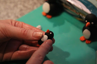 Making model penguins from icing for decorating a christmas cake