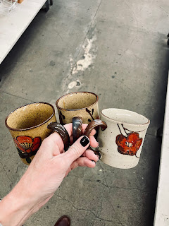 A hand holding three vintage mugs