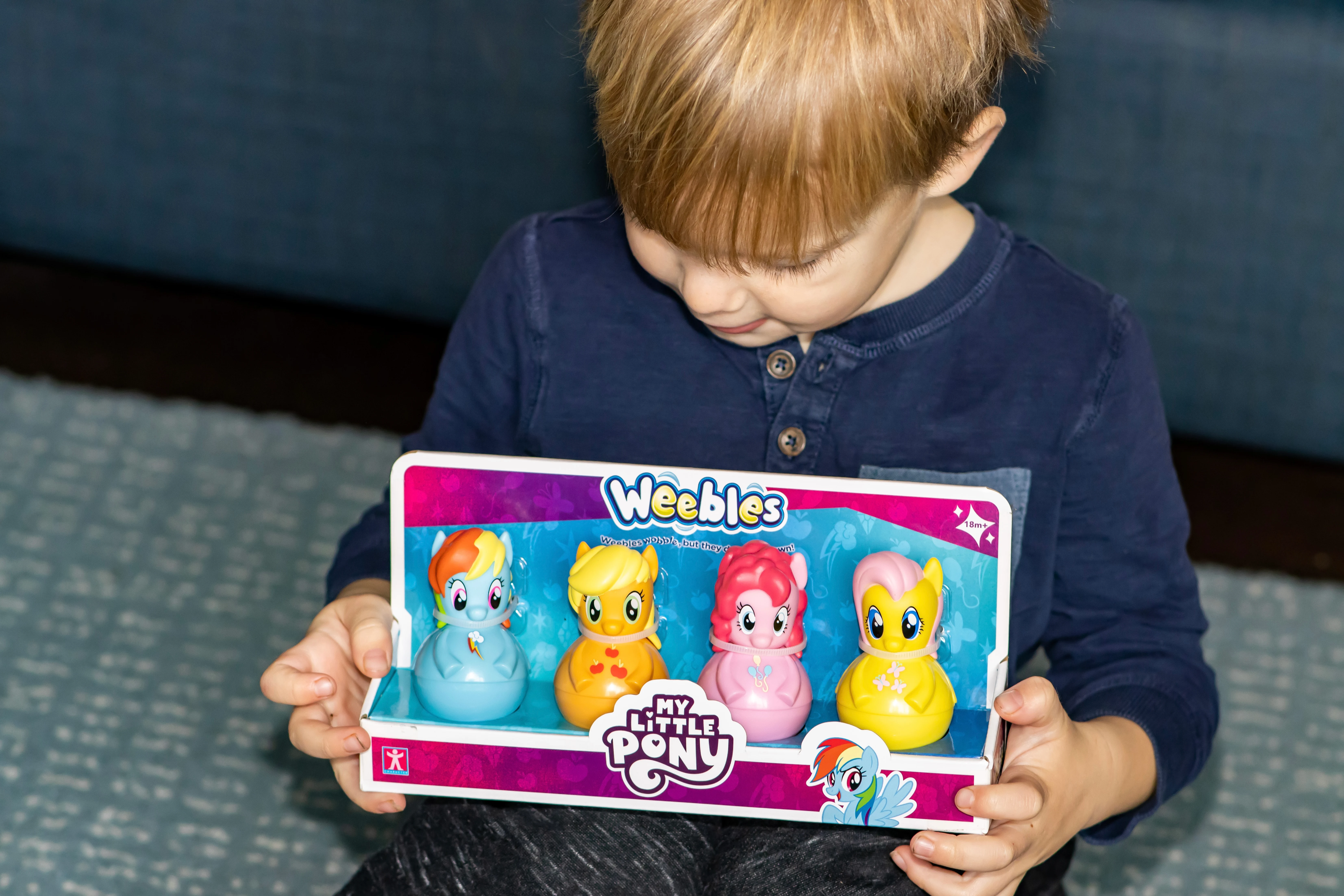 A preschooler holding a 4 pack of My Little Pony Weebles