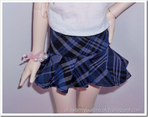 A blue plaid pleated skirt for a doll made from fabric scraps