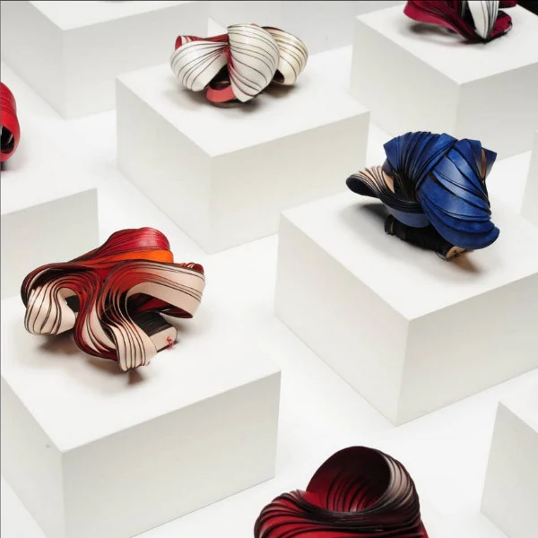 display of shiny paper strips coiled into undulating freestanding forms on small pedestals