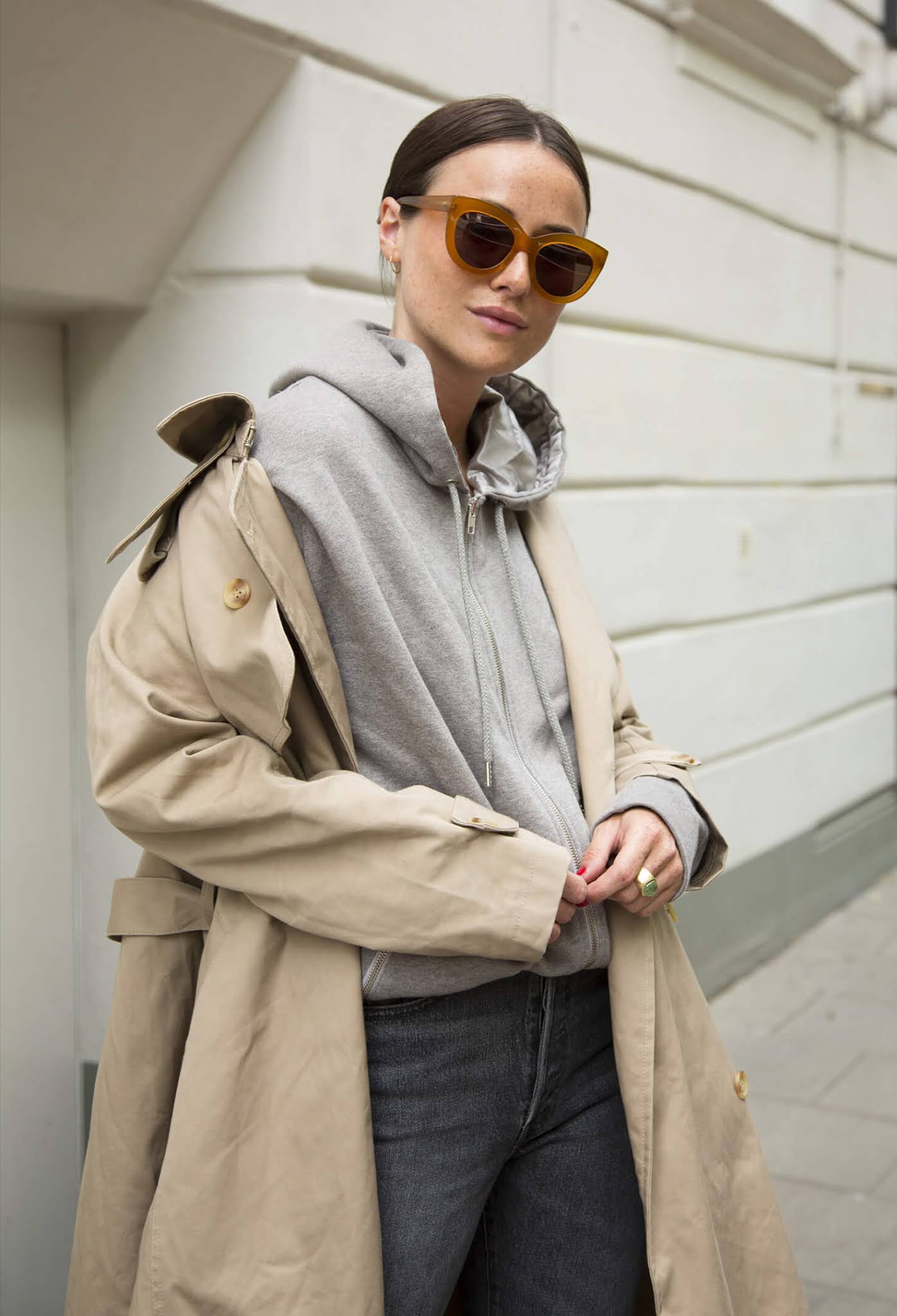 A Hoodie and Trench Coat Make for the Perfect Spring Outfit Combo — Lena Lademann in a classic trench coat, gray hooded sweatershirt, and faded black jeans