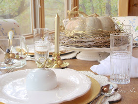 Thanksgiving gold and white table has a cinderella pumpkin with gold and white wreath base