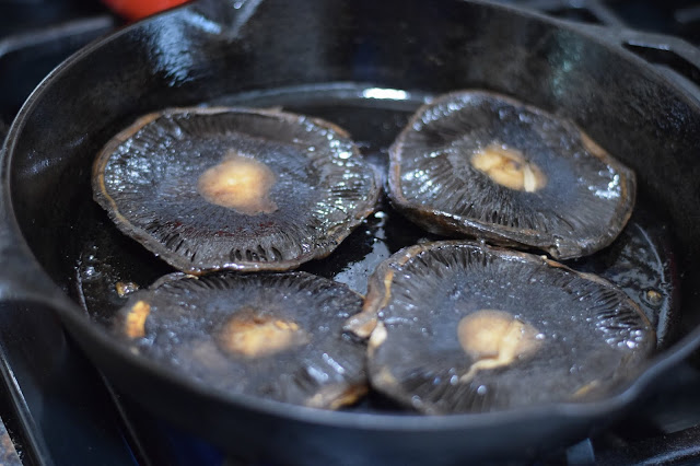 The portobello mushrooms cooking in the pan.