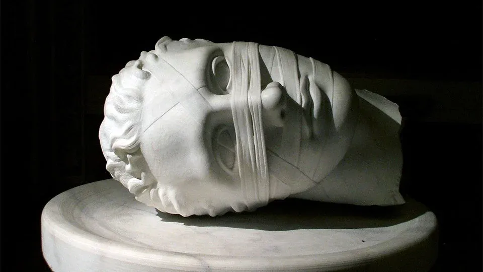 Фрагмент античной мраморной скульптуры: голова молодого человек. На лице застыла маска отстраненности, безразличия и усталости