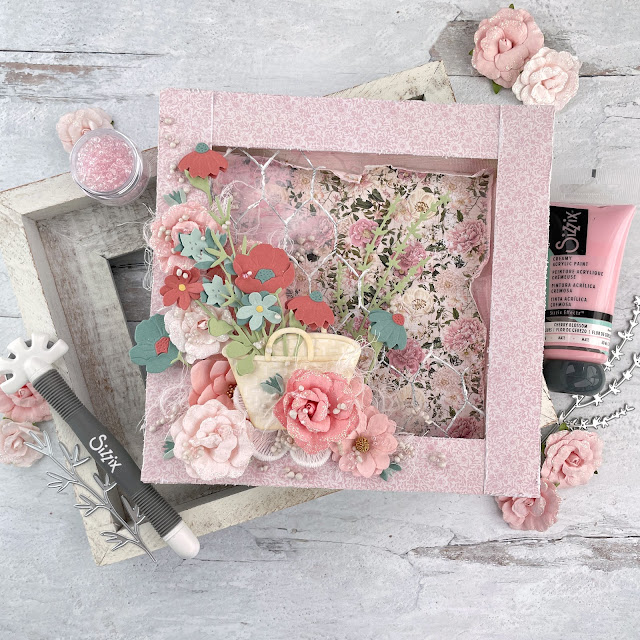 Flower Basket reverse mixed media canvas created with: Sizzix creamy matte paint in cherry blossom, sequin mix in ballet slipper, floral vessels, in the meadow, woodland stems die, muted cardstock, white texture roll; Scrapbook.com cloud whip; Tim Holtz linen distress oxide; Prima miel paper, flowers, art stones