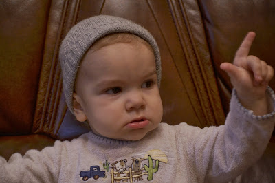 a small girl sitting on the sofa with her hat on