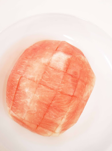 A brain shaped watermelon, cut into bites, on white plate.