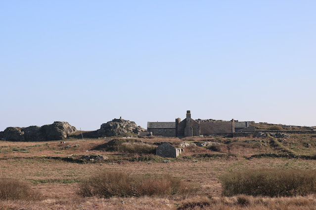 Farm building nestled amongst rocky outcrops and fields.