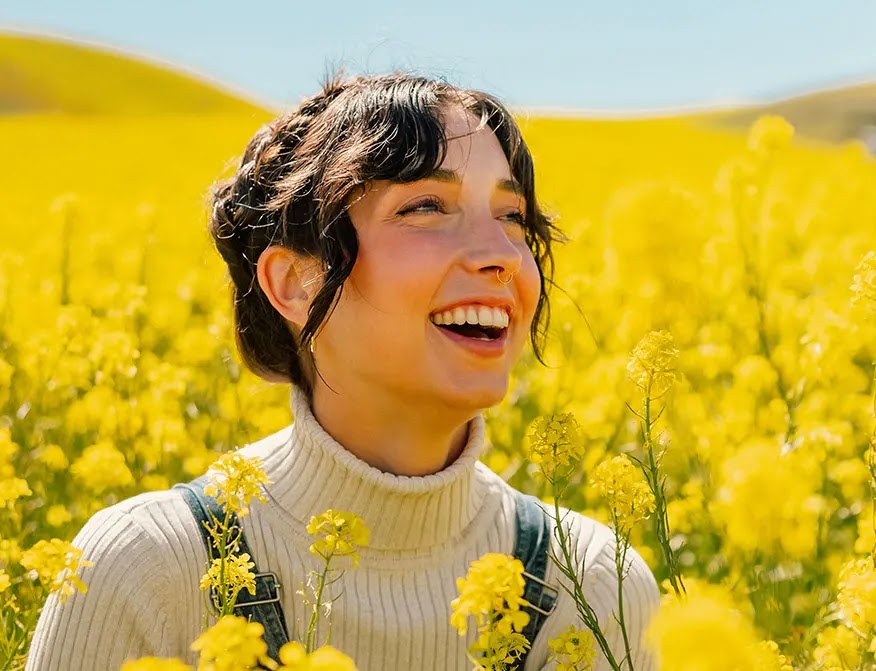 mujer-sonriendo-en-campo-de-flores-amarillas
