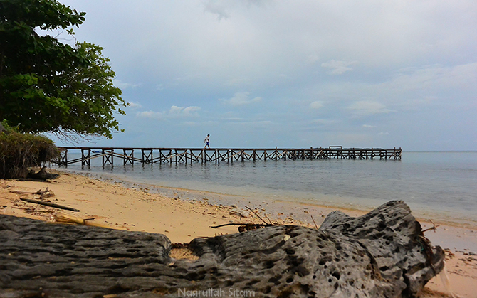 Pemandangan pantai yang ada dermaga kayunya