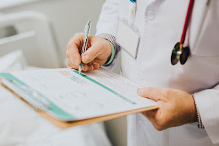 doctor with a wooden board and writing prescription for patient on white paper