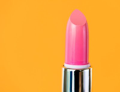 Barra de labios de color rosa sobre fondo amarillo