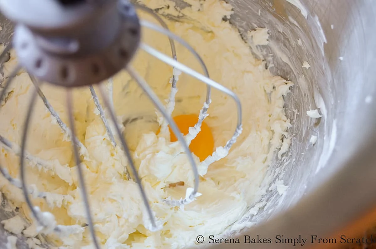 Beaten Cream Cheese in a mixing bowl with an egg yolk in the center.